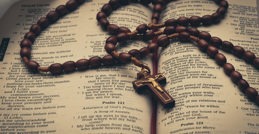A rosary resting on an open Bible, representing Catholic prayer and study.