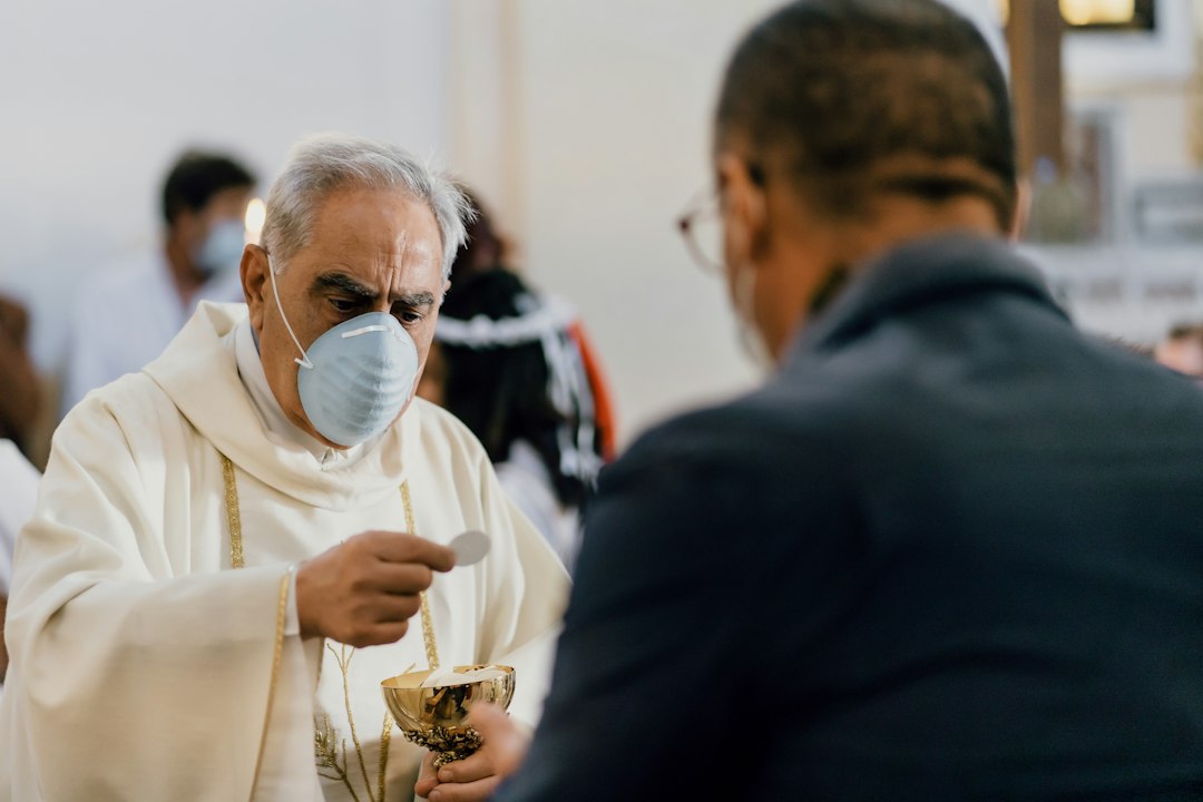 A Catholic priest distributing Holy Communion, representing Christ present to His people through the sacraments.
